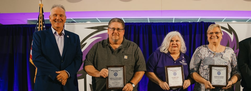 The winners of the 2025 Staff Awards stand between President Blake and Council Chair Chad Dent, from left to right: Karl Brown, Teri Reckhart, and Dell Mullis